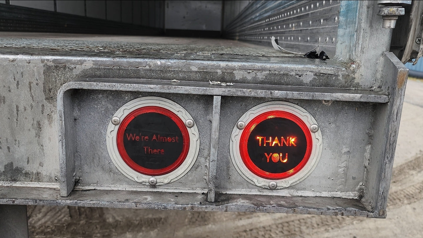 Signal Speak Thank You Tail-Light Overlay illuminated on the right trailer tail light beside a "We're Almost There" brake-light overlay